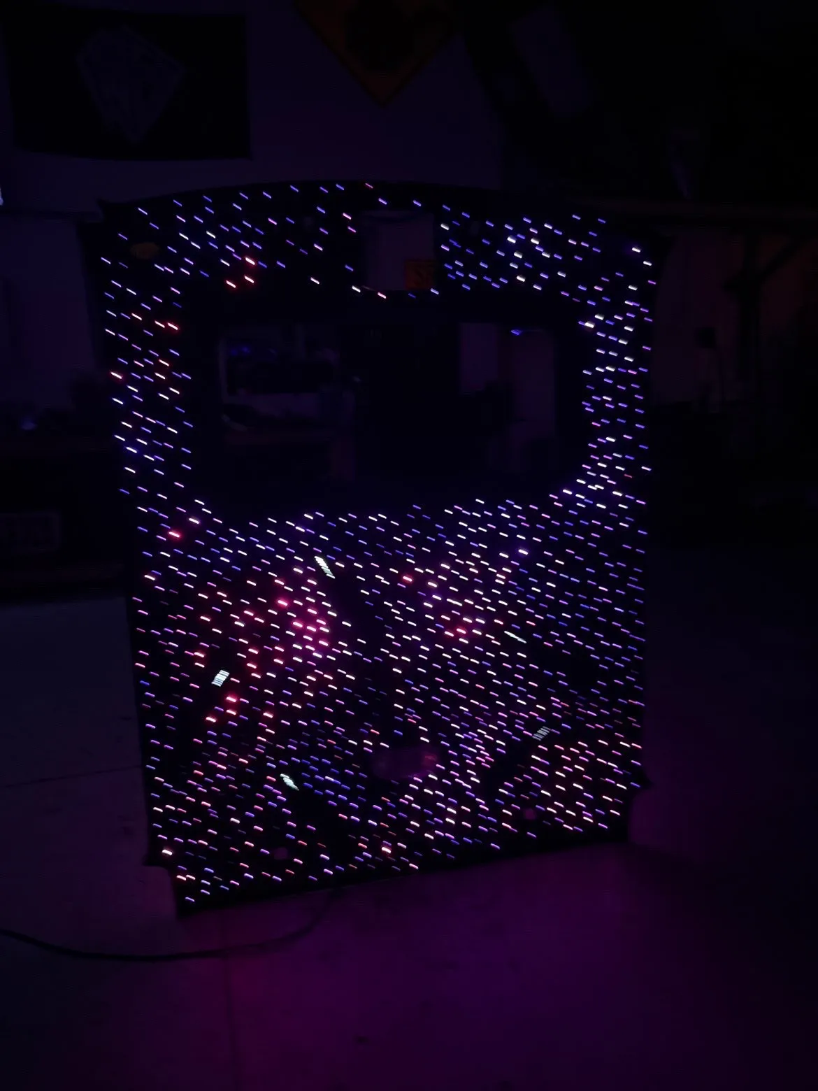 A truck headliner panel standing on the shop floor, its fibre-optic points glowing faint violet and pink in the dark.