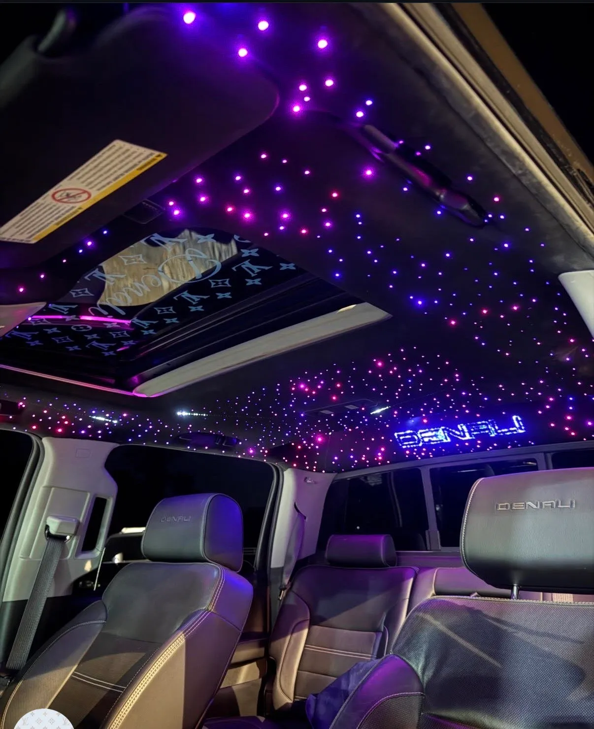 A finished starlight headliner installed in a GMC Yukon Denali, violet and pink stars filling the roof with the Denali name lit up in blue.