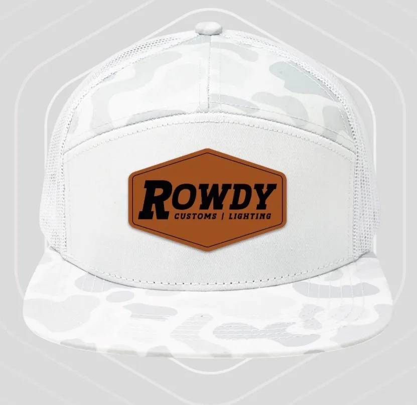 White cap with a pale snow-camouflage brim and side panels, and a leather Rowdy Customs patch.